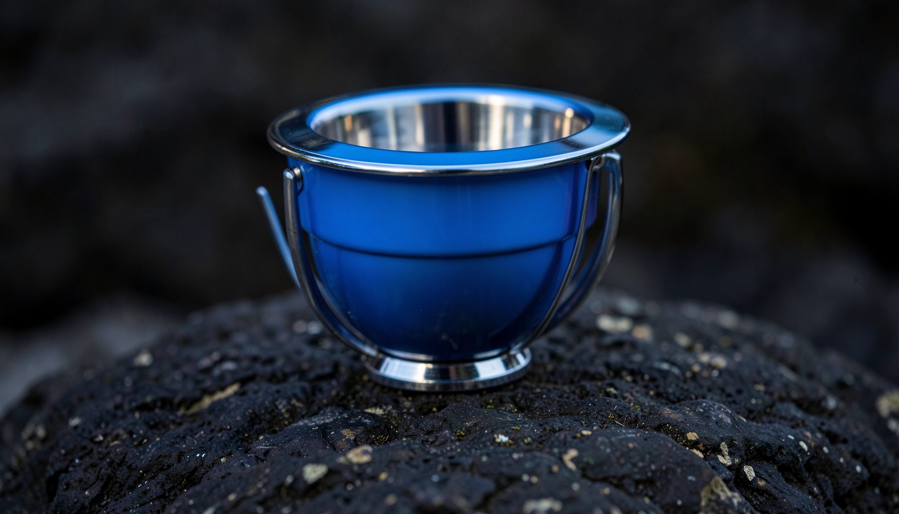 Gros plan d'un popper avec sa cuvette frontale, tons bleu et chrome, posé sur un rocher sombre