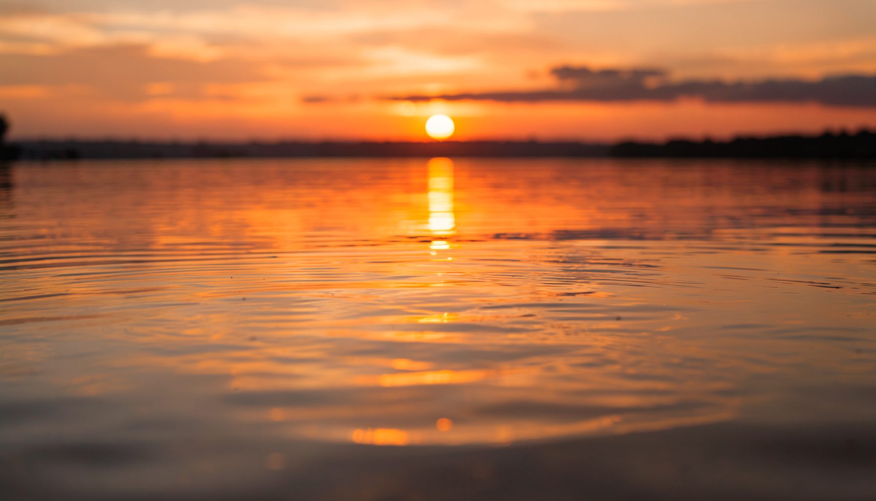 Leurre de surface flottant sur une eau calme au coucher du soleil, reflets dorés et orangés