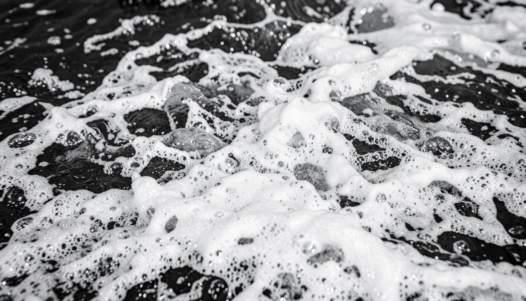Mer agitée avec des gerbes d'écume, tons gris acier et blanc, ambiance puissante