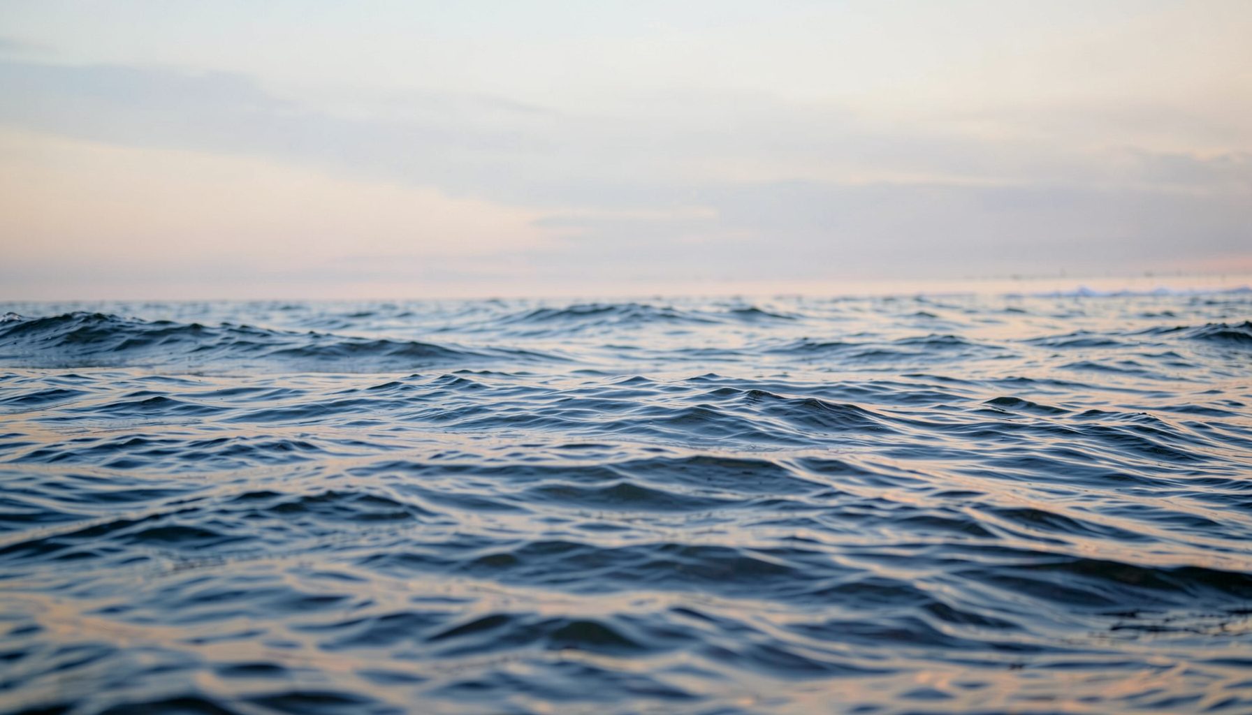 Mer calme au petit matin avec une légère houle, tons bleu-gris et dorés, ambiance sereine
